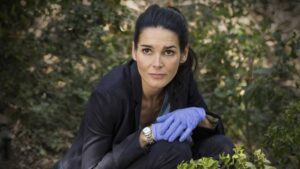 A somber image depicting actress Angie Harmon standing outside her Charlotte residence, reflecting on the tragic incident involving her beloved dog and an Instacart delivery driver.